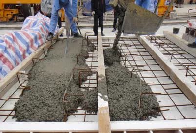 Wet concrete being placed into reinforced precast molds on a factory casting line