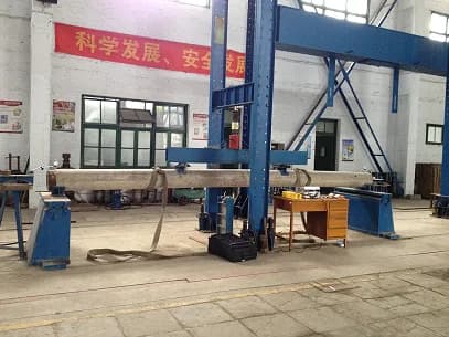 Indoor mechanical load test rig with a circular concrete utility pole and measurement equipment