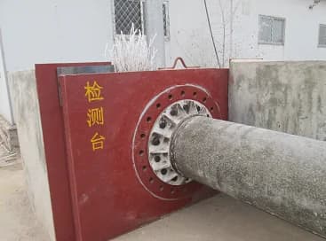 Bolted root restraint fixture holding a cylindrical circular concrete pole for mechanical testing