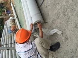 Inspector measuring wall thickness at the end of a circular concrete utility pole