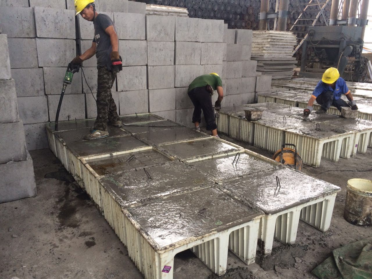 Workers finishing precast concrete cable trough modules during factory production