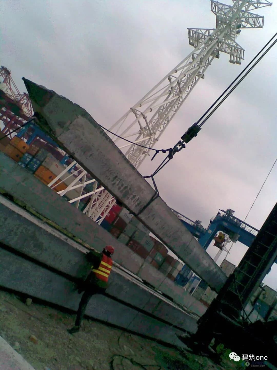 Crane lifting a long precast concrete square pile segment beside a pile rig